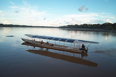 a solar boat on a river piloted by Achuar Indigenous people